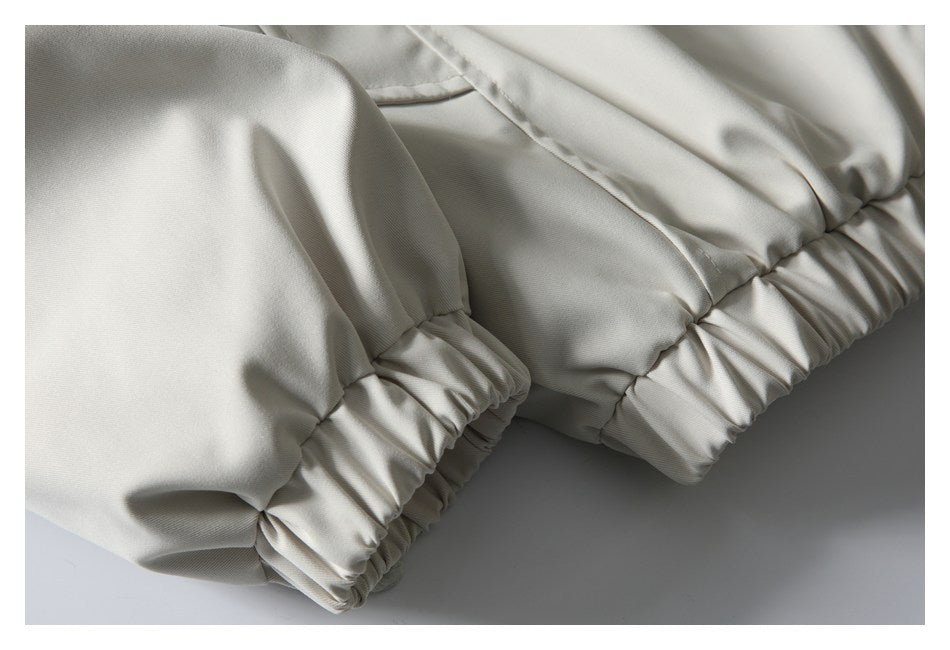 Close-up of gathered elastic edges and stitched panels on an off-white garment.