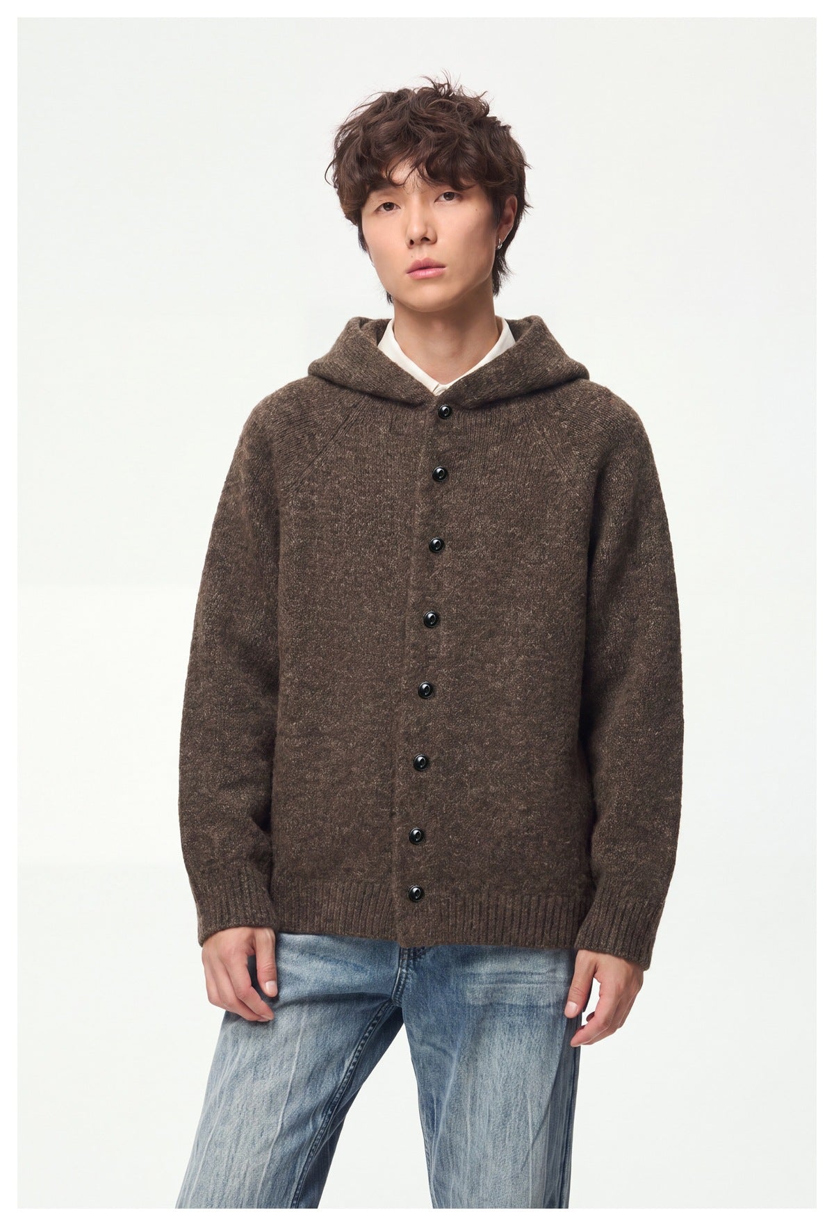 Man wearing a brown hooded knit button-front jacket with light blue jeans, front view