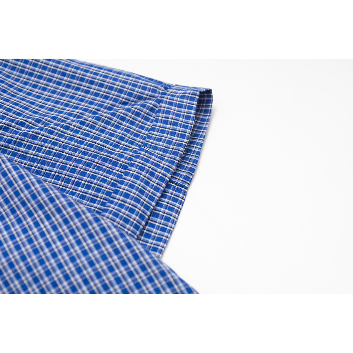 Close-up of blue plaid shirt fabric and a folded, stitched edge against a white background.