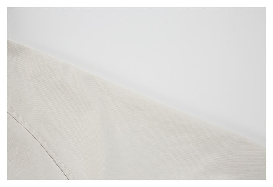 Close-up of the off-white jacket sleeve and a curved seam against a plain background.