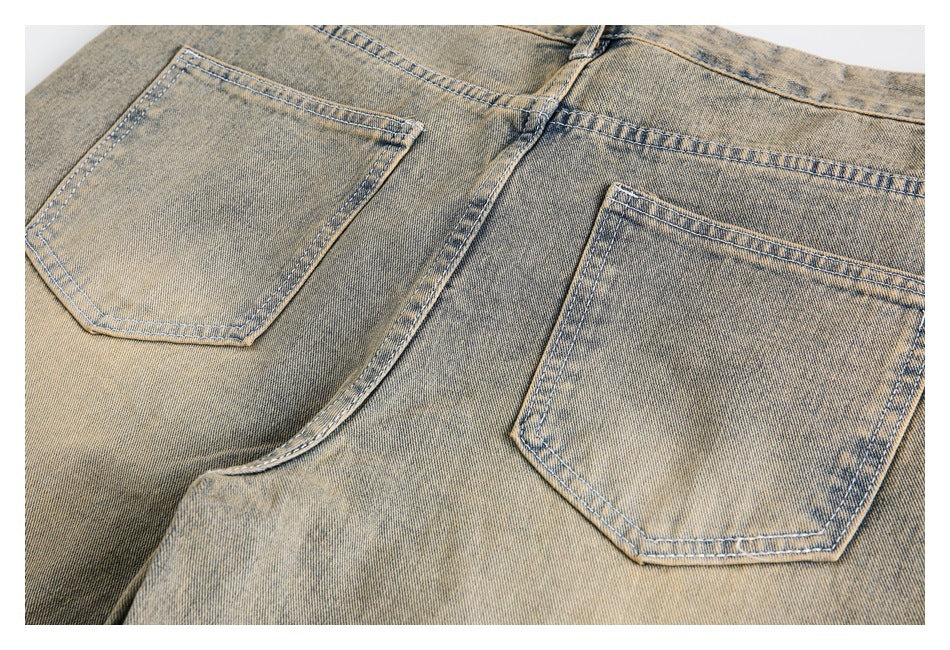 Close-up of two back pockets and stitching on faded tan denim jeans.