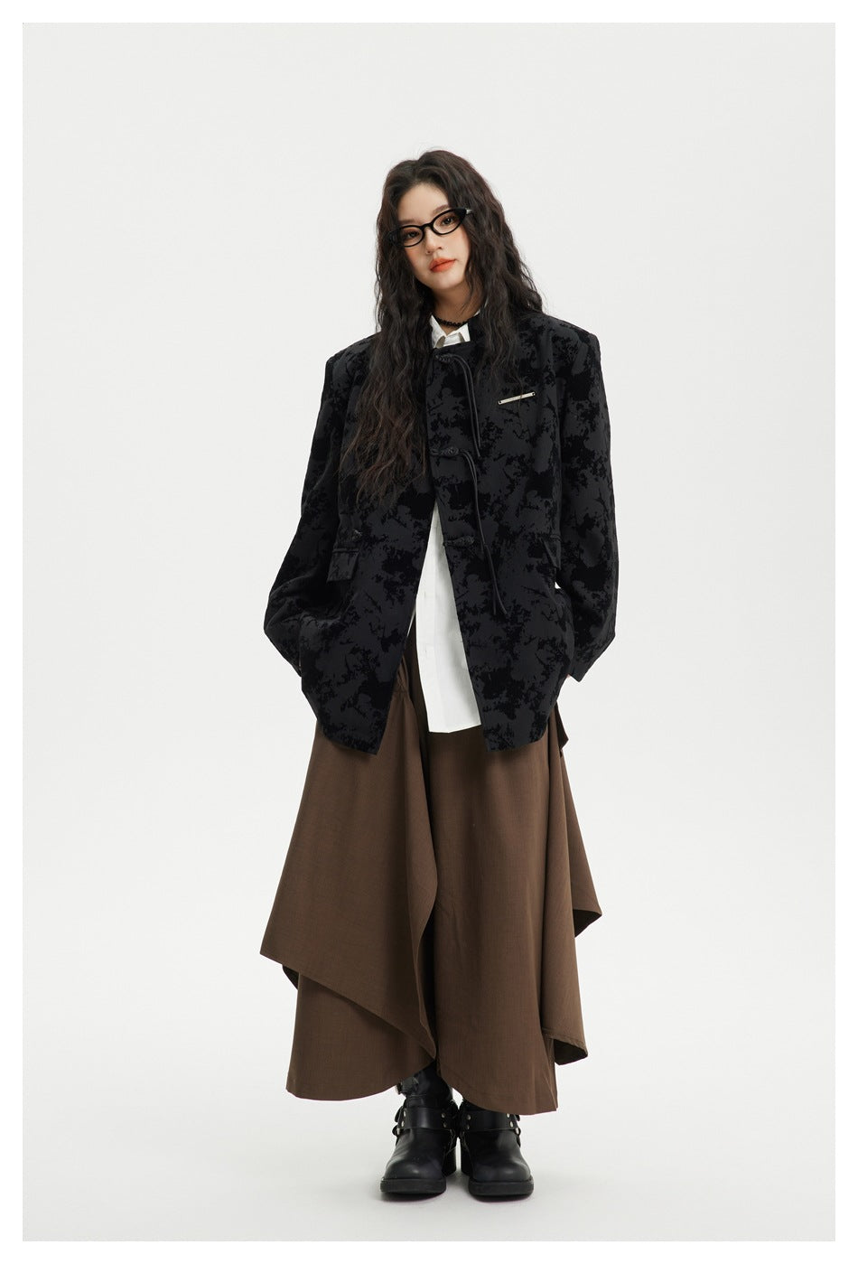 Model wearing the black abstract-print jacket with frog closures over a white shirt and layered brown skirt.