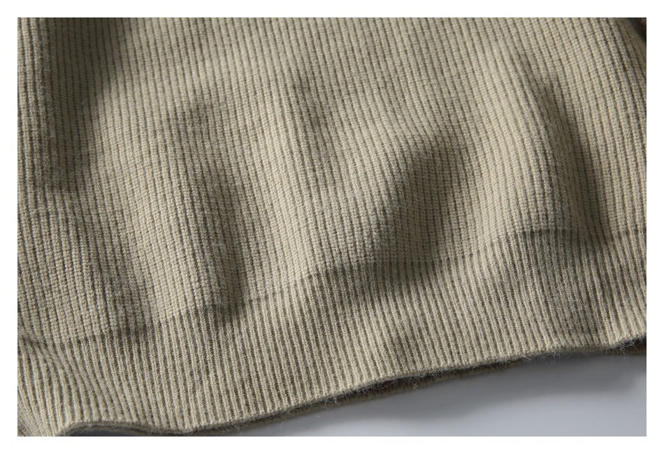 Close-up of the beige sweater’s ribbed knit fabric and finished lower hem.