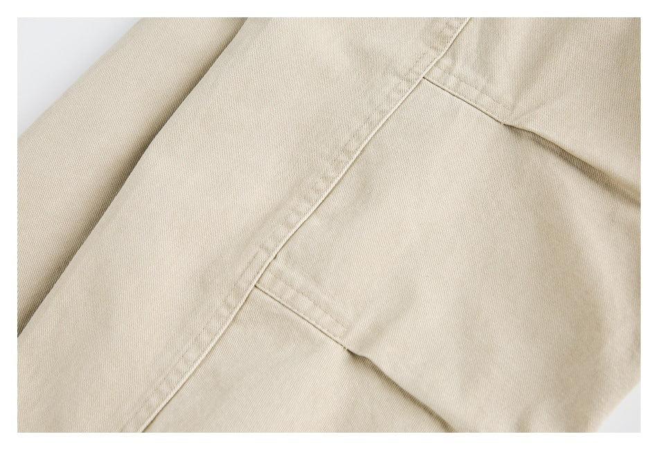 Close-up of a stitched pocket opening on beige garment fabric.