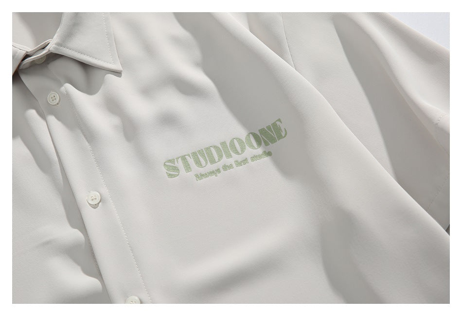 Close-up of an ivory button-front shirt with a pale green STUDIOONE chest print.