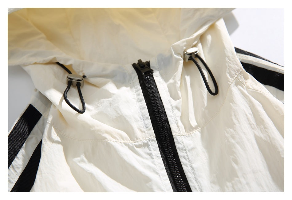 Close-up of an ivory garment with a black front zipper, drawcord toggles and black stripe trim.