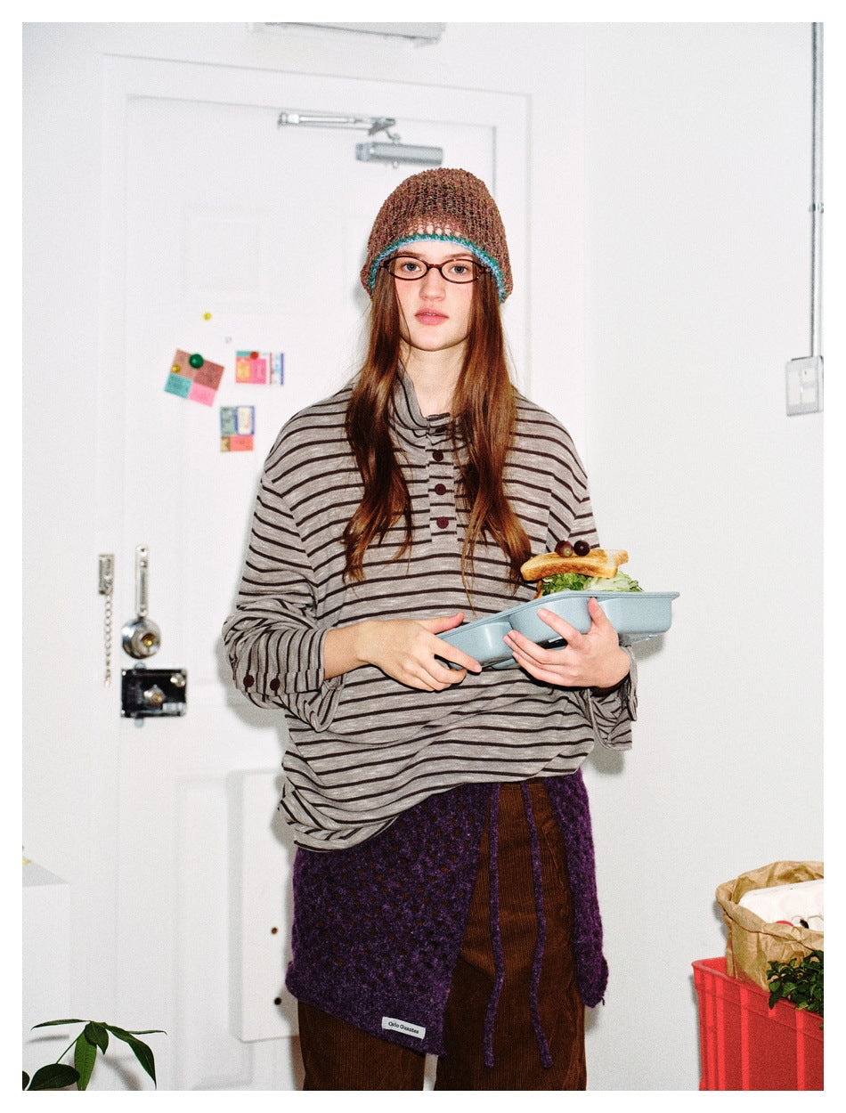 Close view of a model wearing an oversized gray-and-black striped high-neck henley with button details.