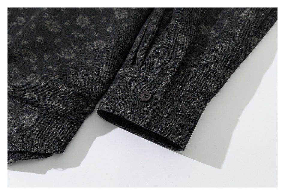 Close-up of a dark charcoal garment sleeve cuff with a button and subtle mottled pattern.