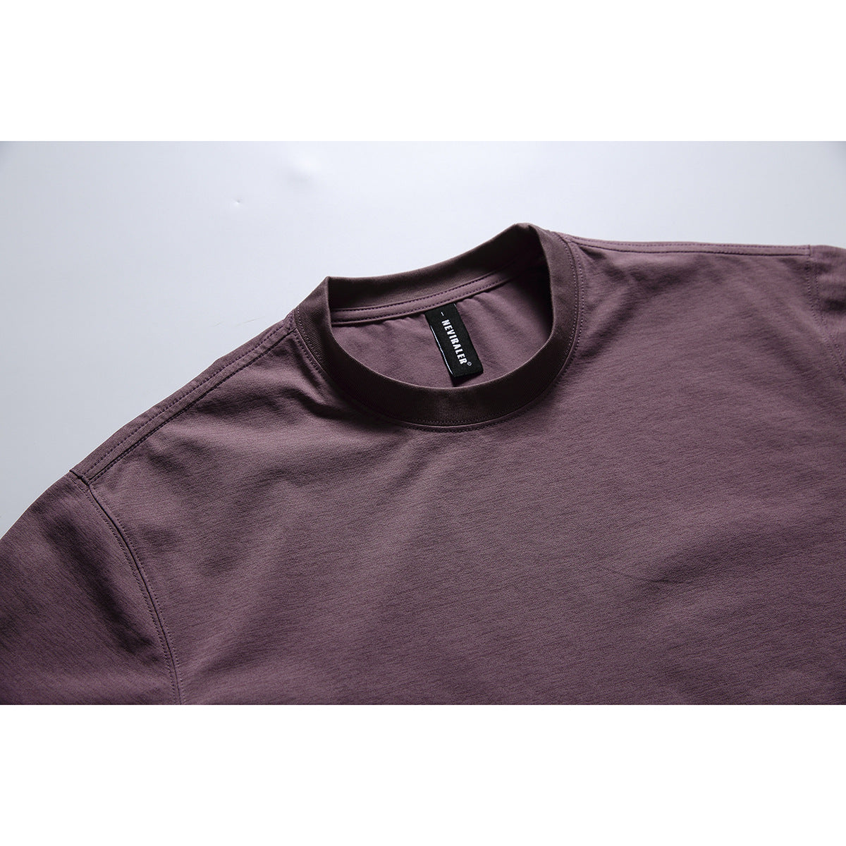 Close-up of a dark plum crew-neck T-shirt showing the collar stitching and inner neck label.