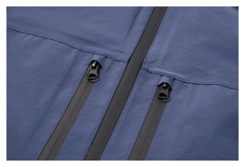 Close-up of a blue jacket showing two vertical black zip pockets beside the main zipper.