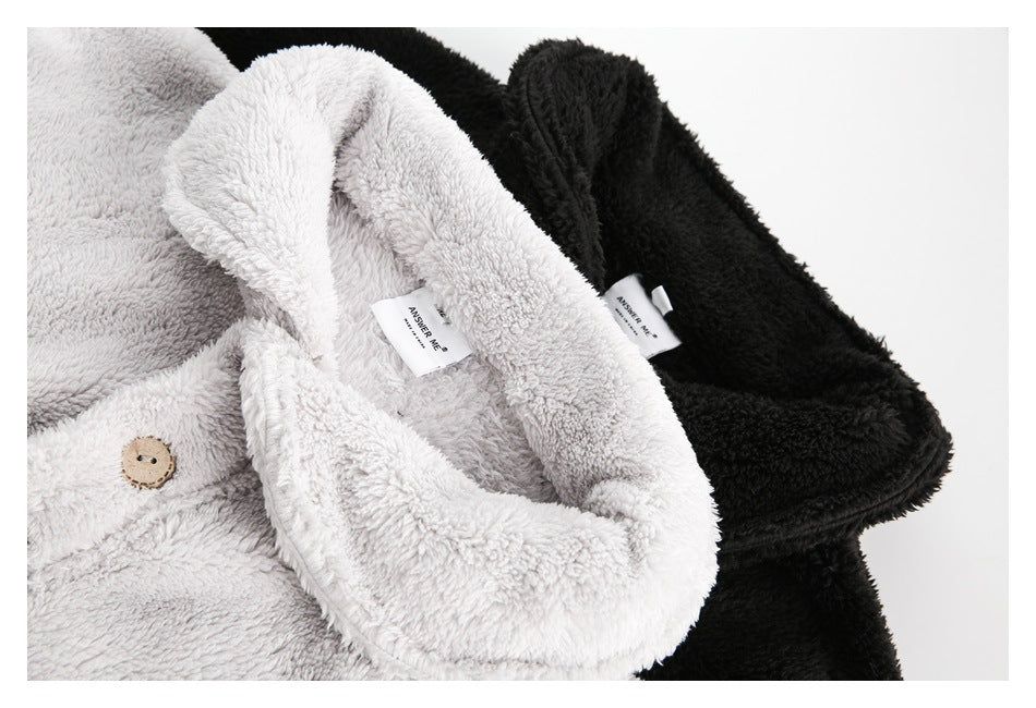 Close-up of light gray and black plush pullovers showing their collars, buttons and attached neck labels.