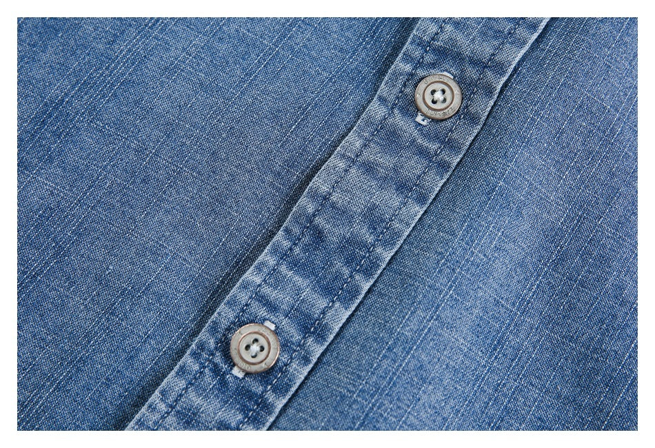 Close-up of a blue denim button placket with two gray buttons and visible stitching.
