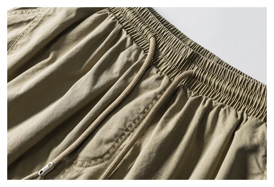 Close-up of khaki shorts showing the gathered elastic waistband, drawcords and curved front pocket.