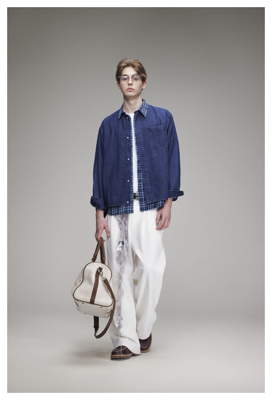 Front view of a model wearing a blue denim overshirt with blue plaid trim and white wide-leg trousers.
