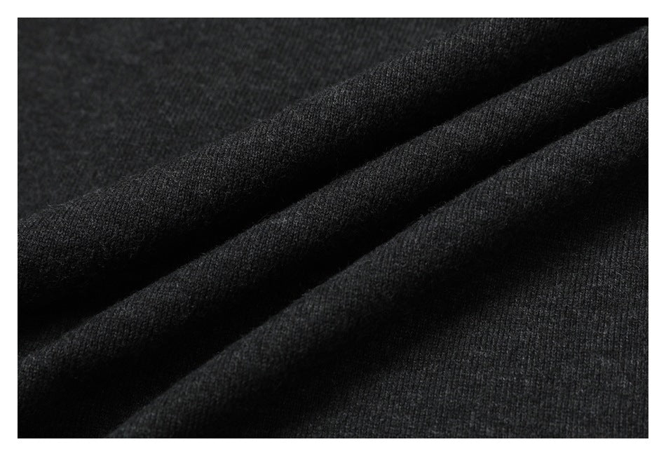 Close-up of dark charcoal knit fabric arranged in soft diagonal folds.