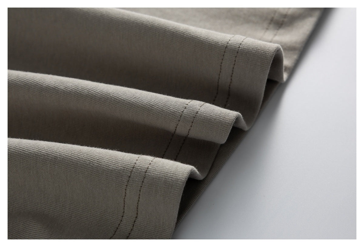 Close-up of a gray-taupe garment hem with parallel rows of stitching and layered folds.