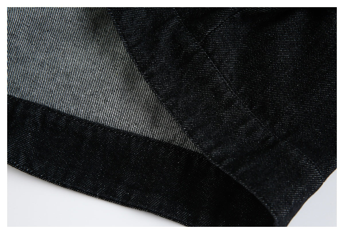 Close-up of black garment fabric folded back to reveal its lighter gray reverse and stitched edges.