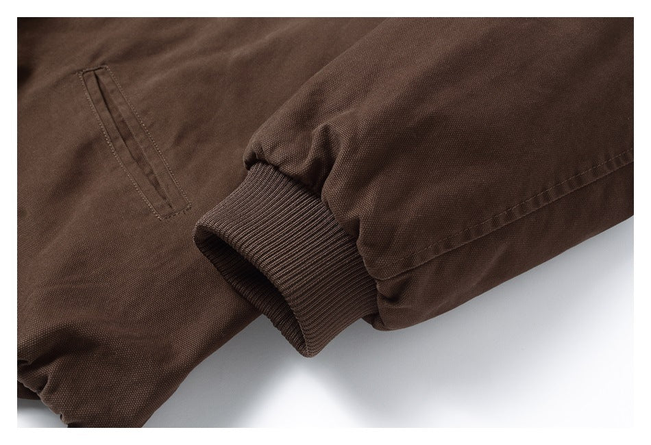 Close-up of a dark brown jacket sleeve with a ribbed cuff and narrow welt pocket.