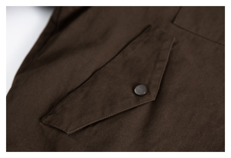 Close-up of a brown jacket’s angled pocket flap and dark snap button.