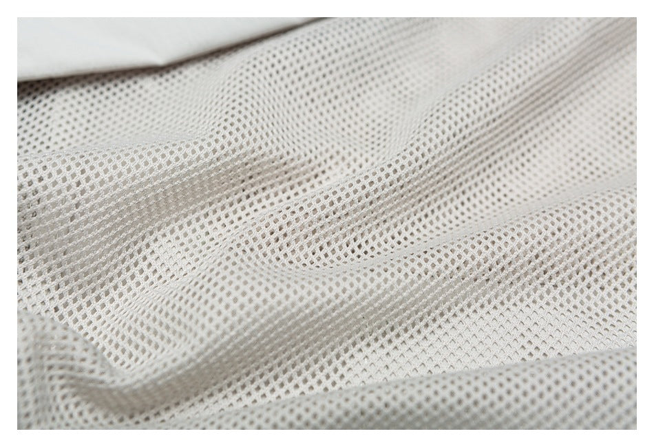 Close-up of pale gray open mesh fabric with a small section of solid fabric at the top edge.