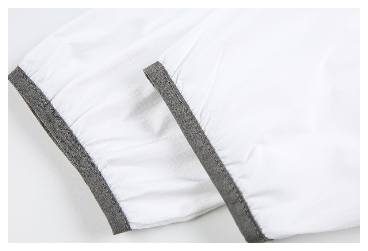Close-up of white garment fabric with dark gray binding along two edges.