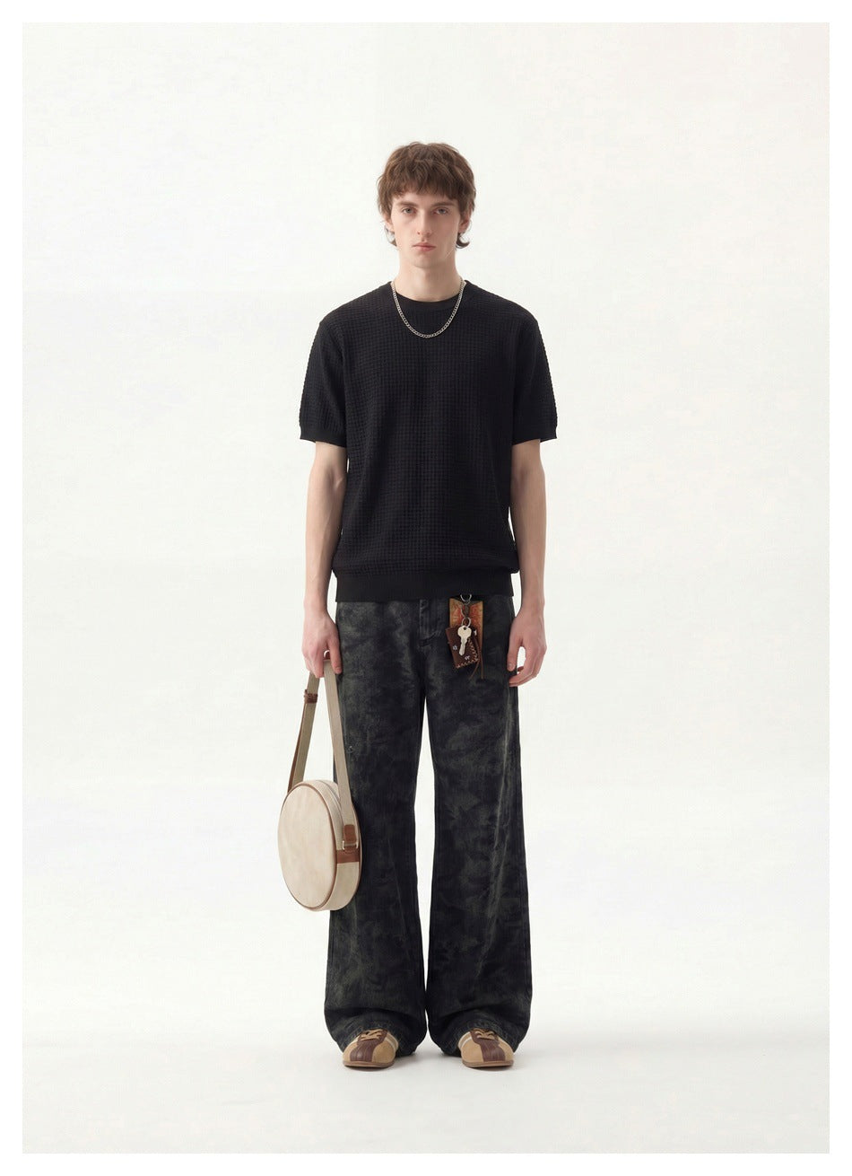 Model wearing a black waffle-knit short-sleeve crew neck top with chain necklace, dark pants and a round bag, full-length