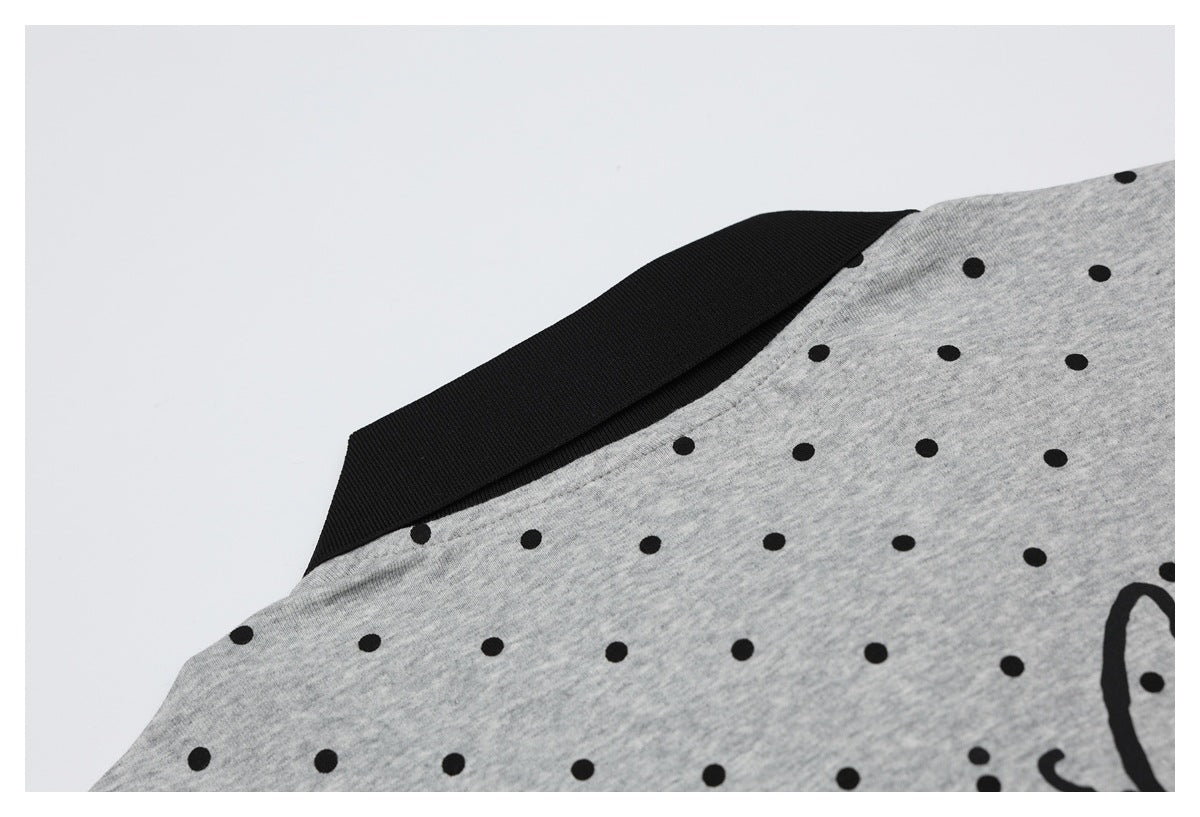 Close-up of the gray dotted shirt's black collar and shoulder, with part of a black graphic visible.