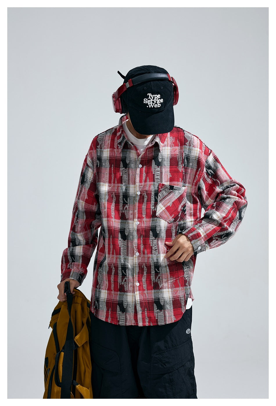 Close view of a model wearing a red, black and white plaid button-up shirt with a single chest pocket.