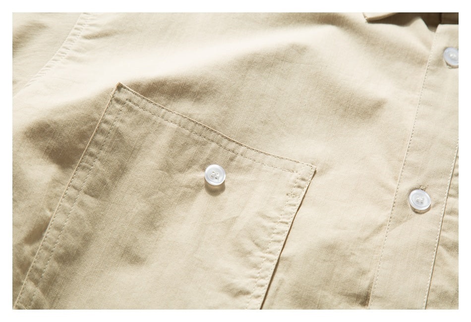 Close-up of a beige shirt's buttoned chest pocket and front buttons.