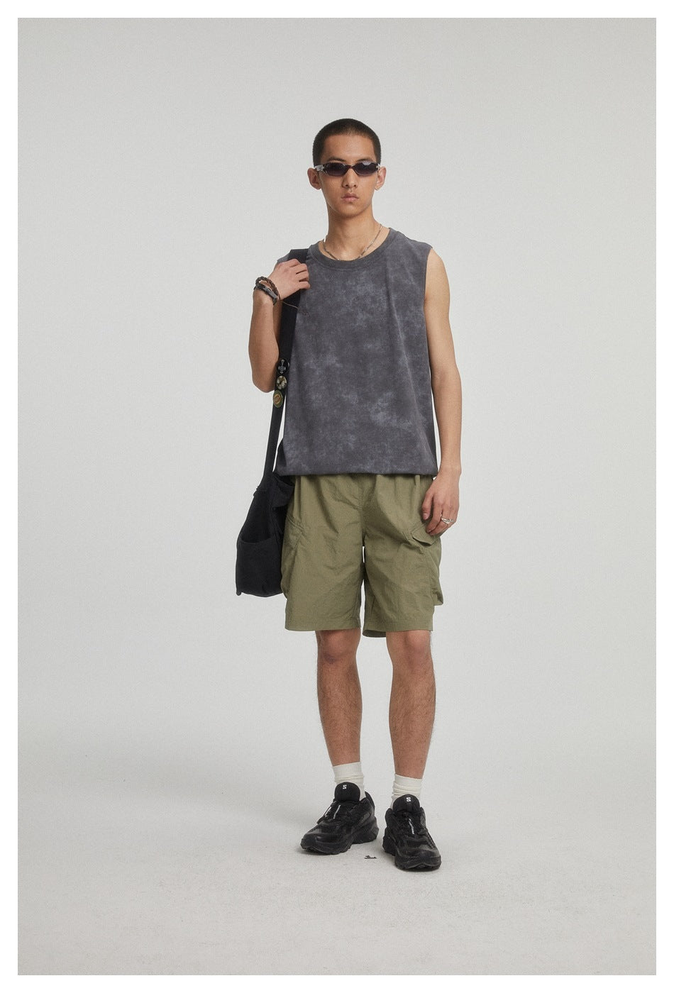 Model wearing a charcoal sleeveless top and olive cargo shorts, facing forward.