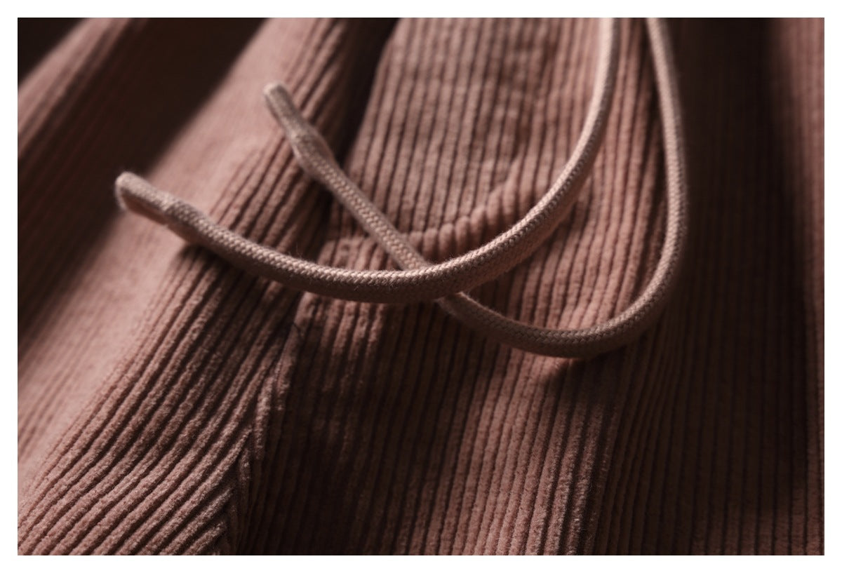 Detail of dusty rose ribbed trousers with braided drawstrings resting across the fabric.
