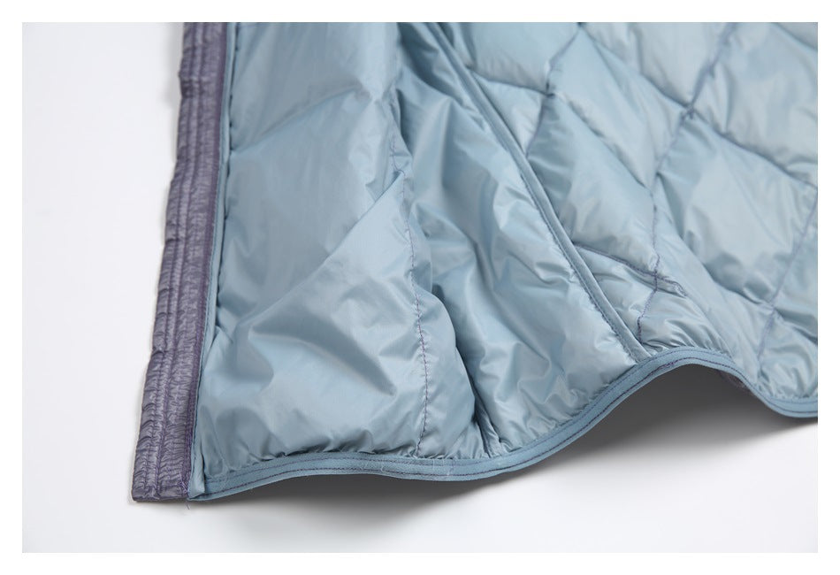 Close-up of the light blue-gray quilted garment's stitched edge and contrasting purple-gray trim.