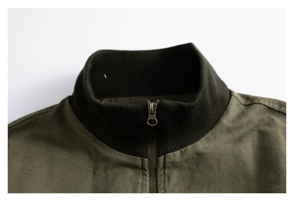 Close-up of an olive jacket’s dark ribbed stand collar and front zipper.