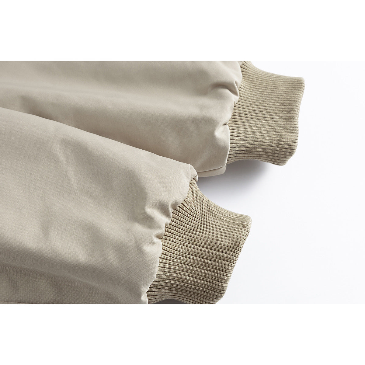 Close-up of beige jacket sleeves ending in ribbed knit cuffs.