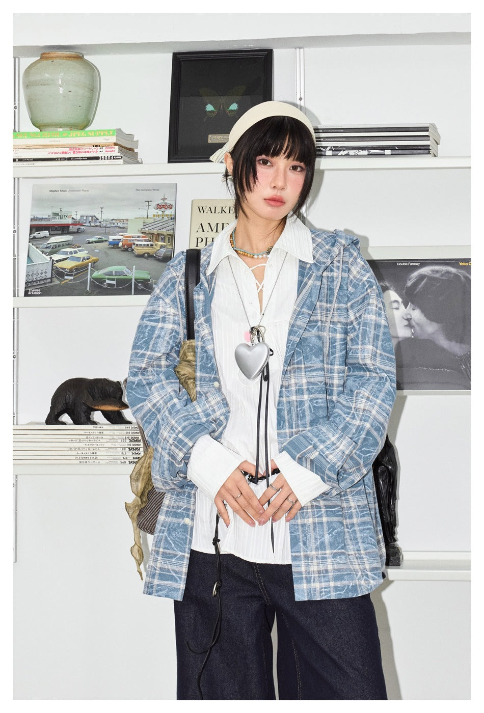 Model wearing an open blue plaid hooded shirt jacket over a white shirt and dark wide-leg jeans