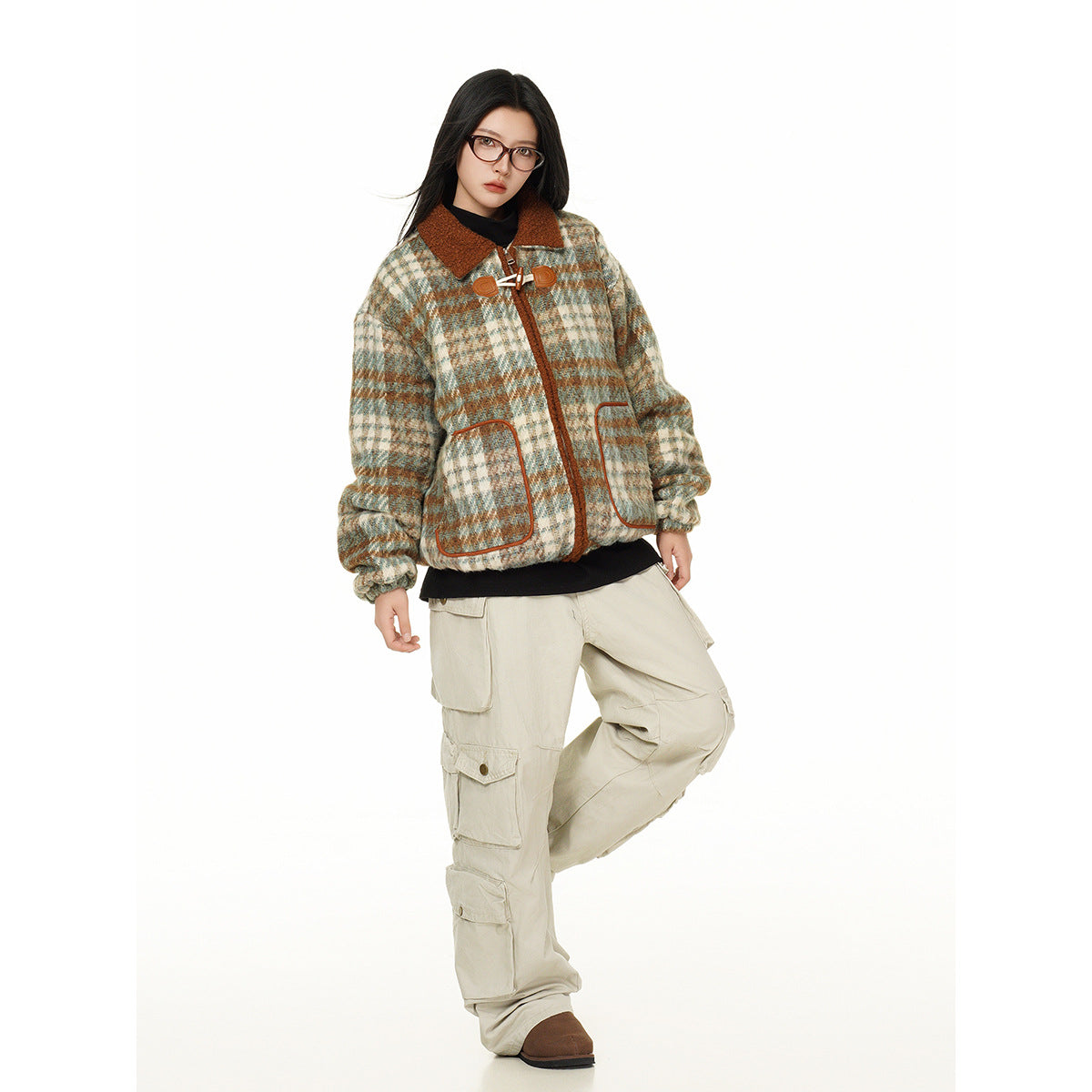 Full-length model wearing a cream, teal, and rust plaid jacket with a rust collar and toggle closures.