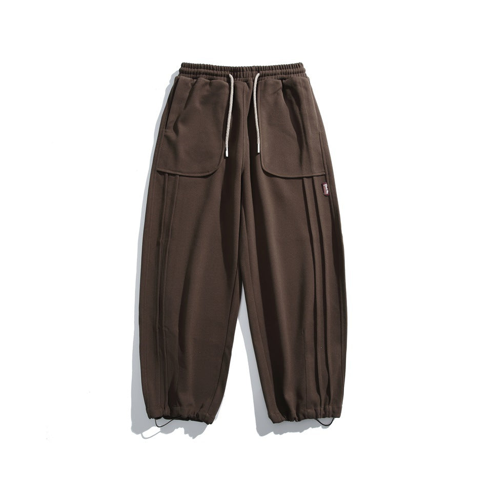 Brown cargo pants displayed flat, with an elastic waist, white drawstrings, large front pockets, and gathered hems.