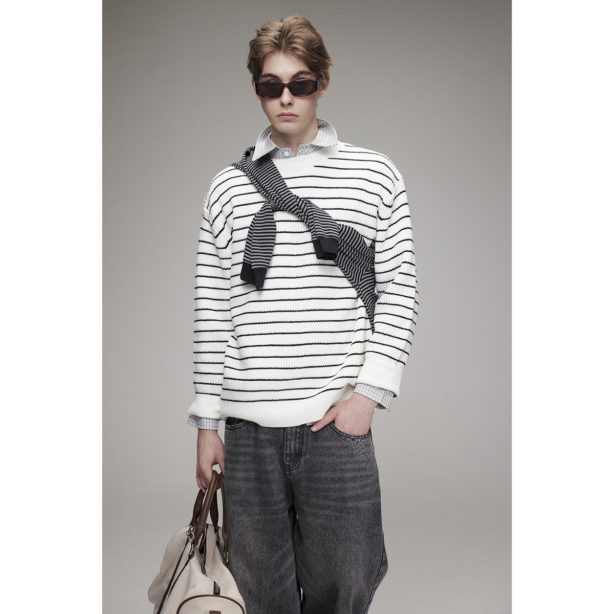 Model wearing a white sweater with thin black horizontal stripes and a dark striped scarf draped diagonally.