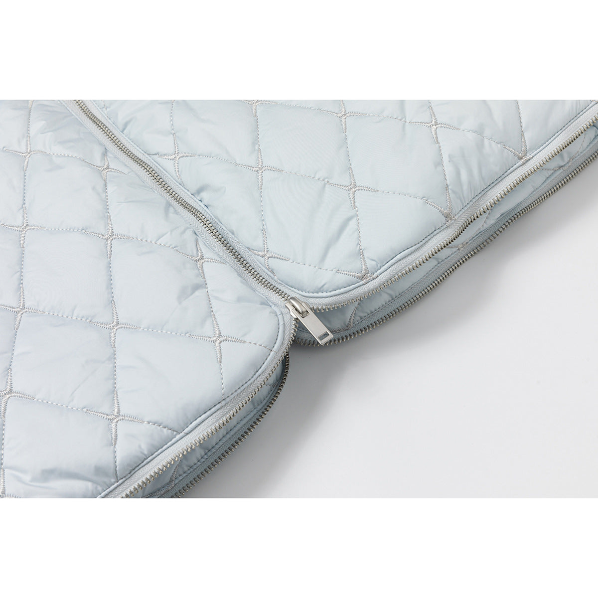 Close-up of pale blue diamond quilting and the vest's silver zipper.