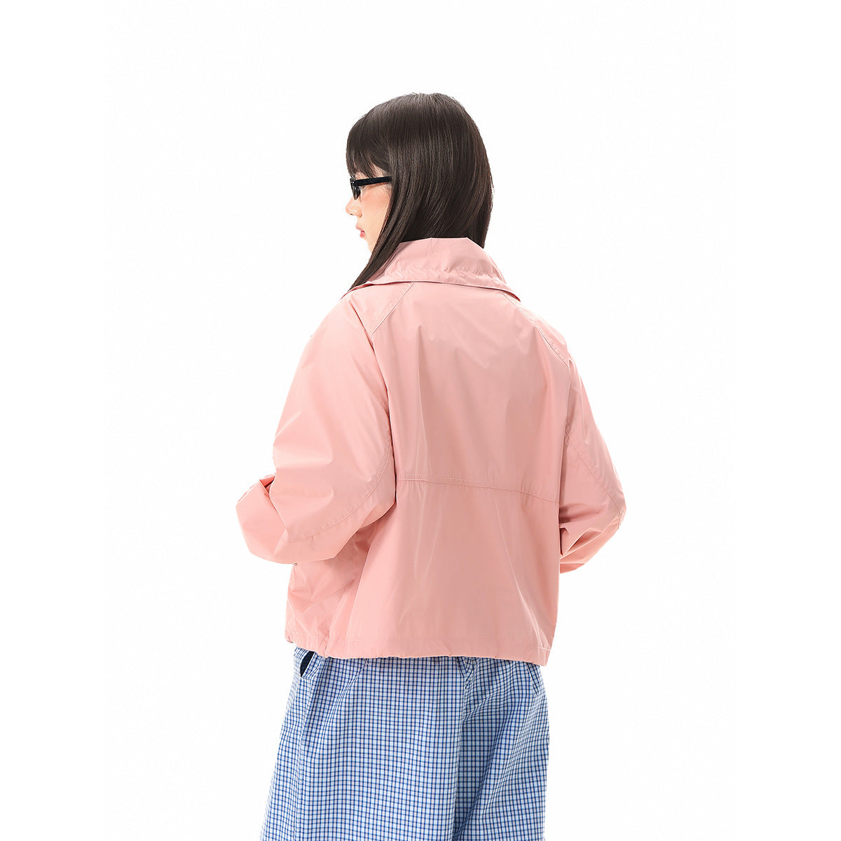 Back view of a model wearing a light pink jacket with a high collar and blue checked trousers.