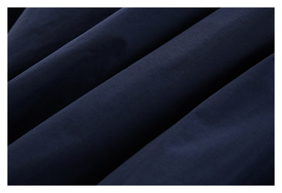 Close-up of smooth dark navy jacket fabric arranged in folds.