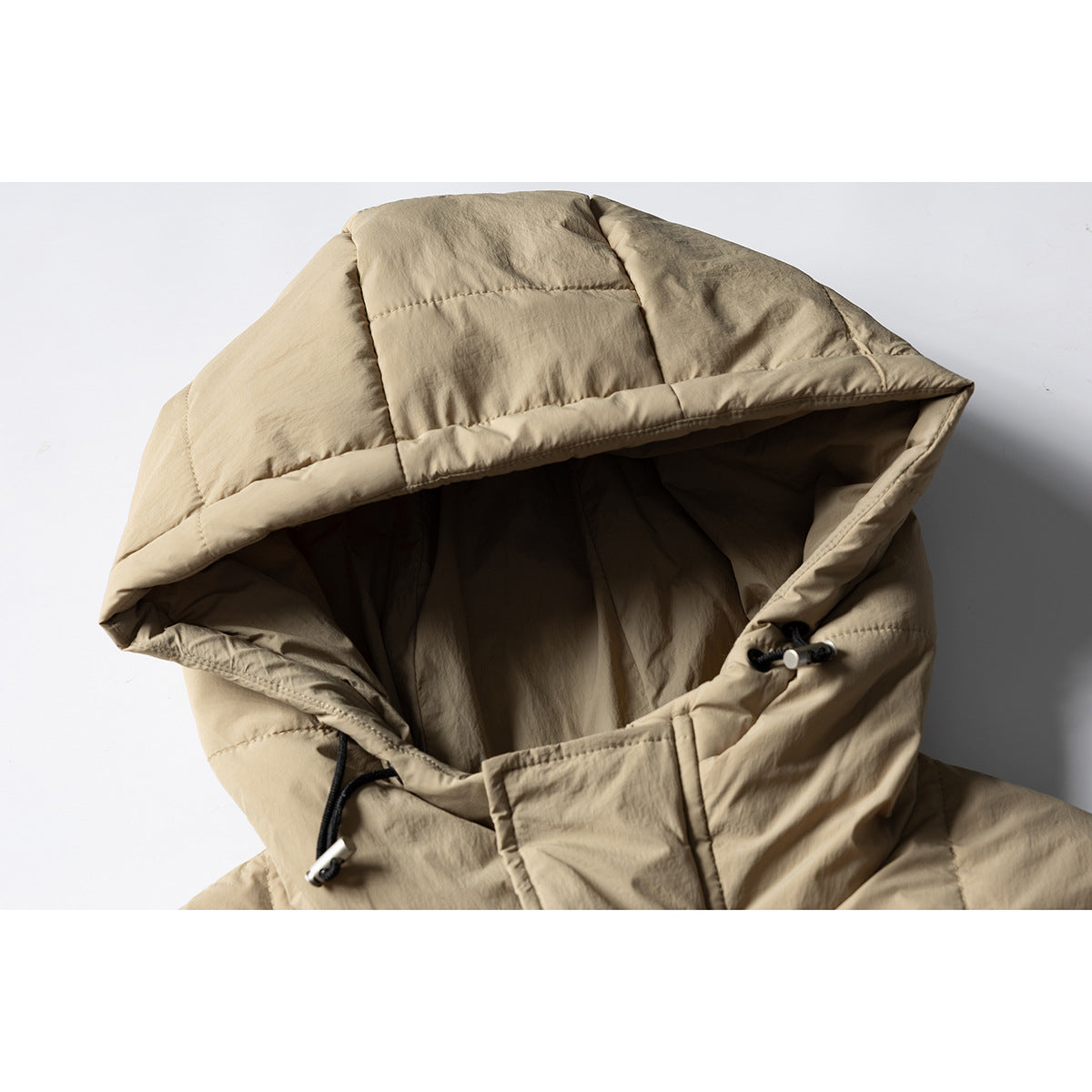 Close-up of a tan quilted jacket hood with black drawcords and toggles.