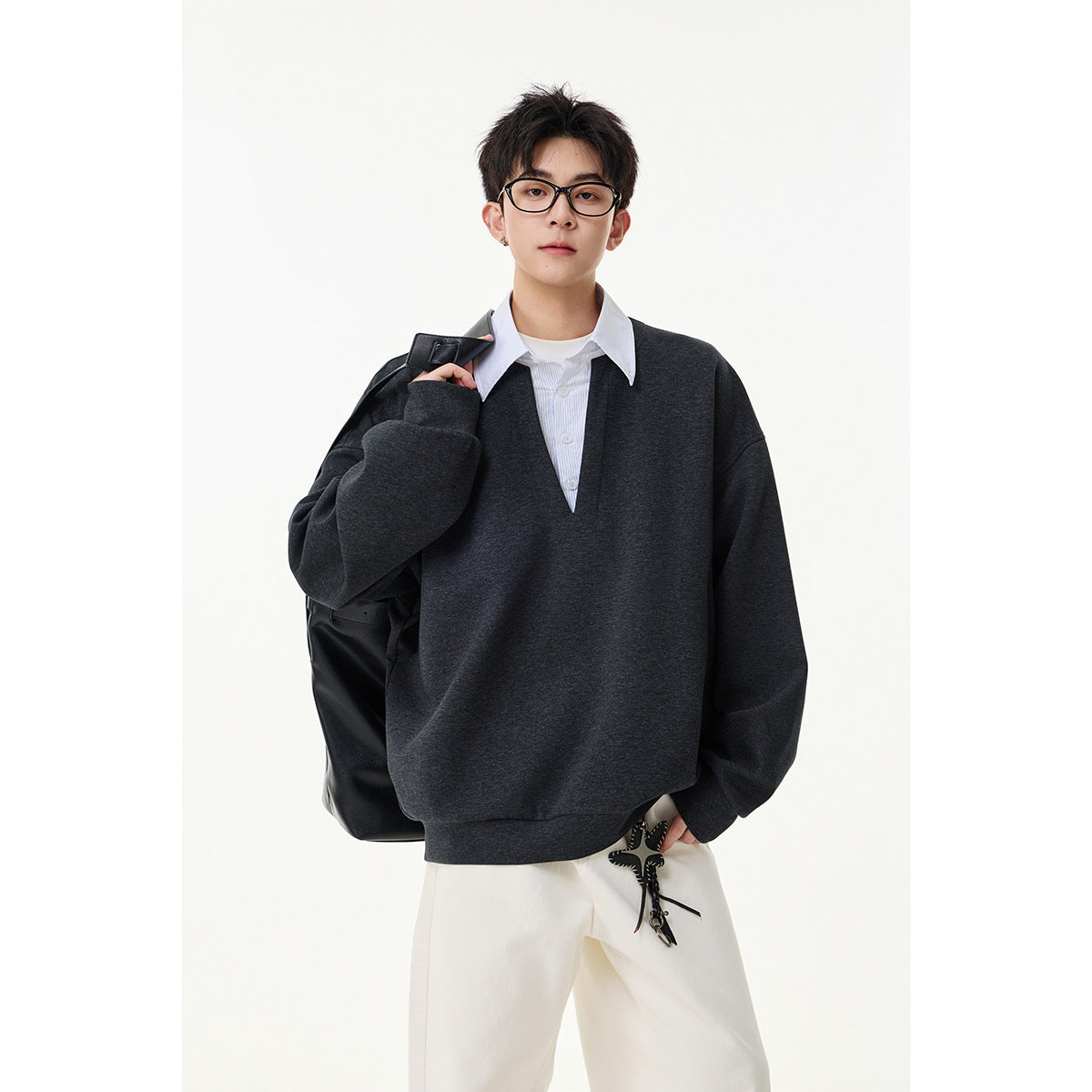 Model wearing a charcoal oversized V-neck sweatshirt layered over a white collared shirt, shown from the front.