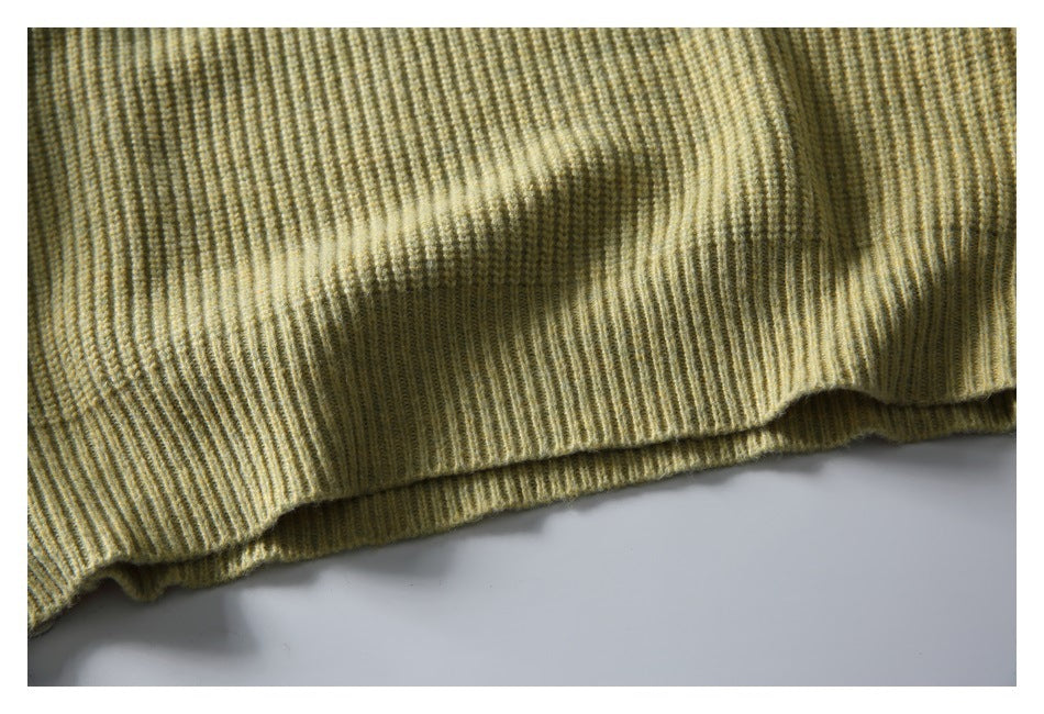 Close-up of the olive-beige sweater's ribbed knit fabric and hem edge.