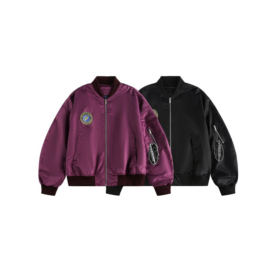 Two front views of zip-front bomber jackets, one purple and one black, each with a chest patch and sleeve pocket.