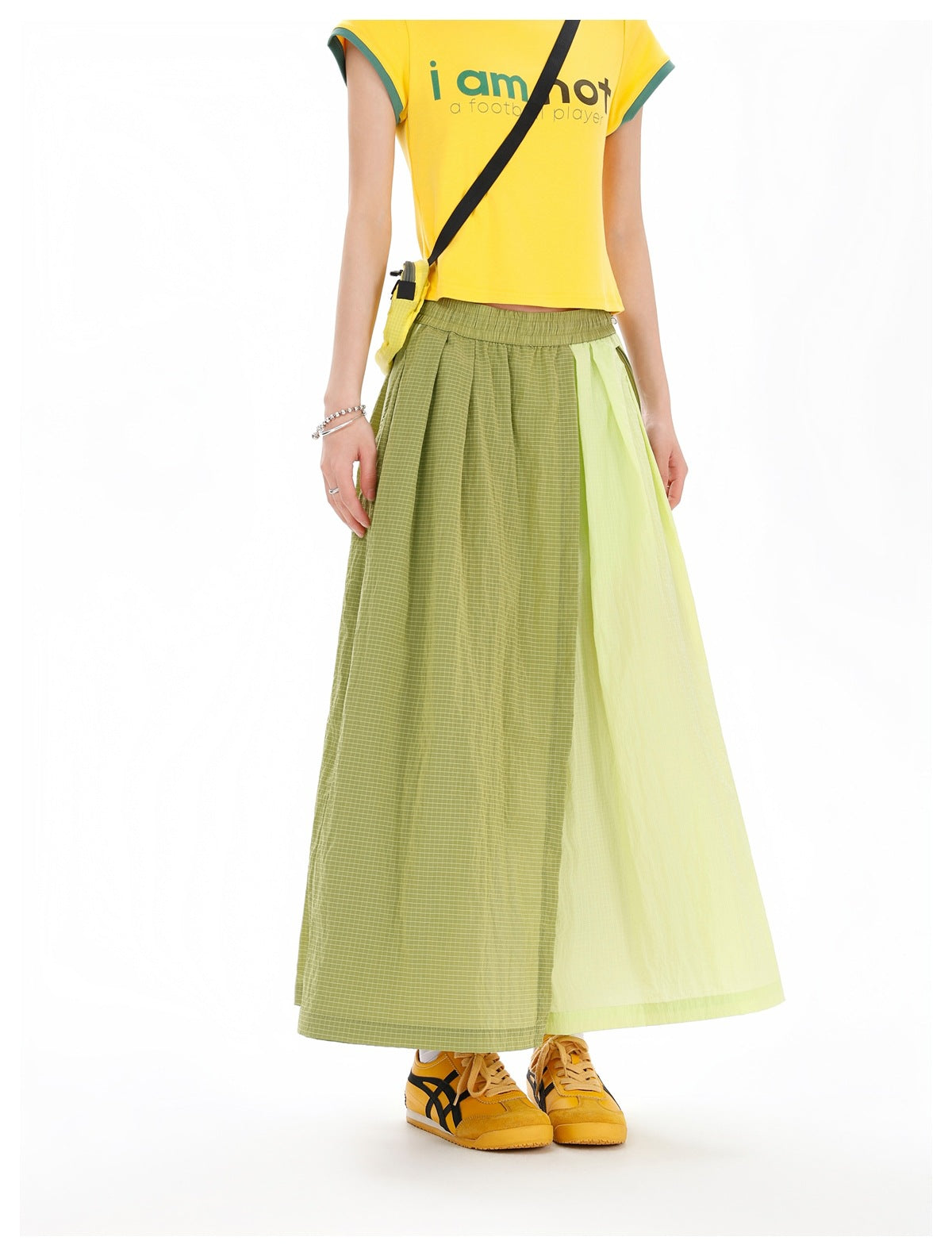 Cropped front view of a model wearing an olive checked and pale-chartreuse panelled maxi skirt with a yellow T-shirt.
