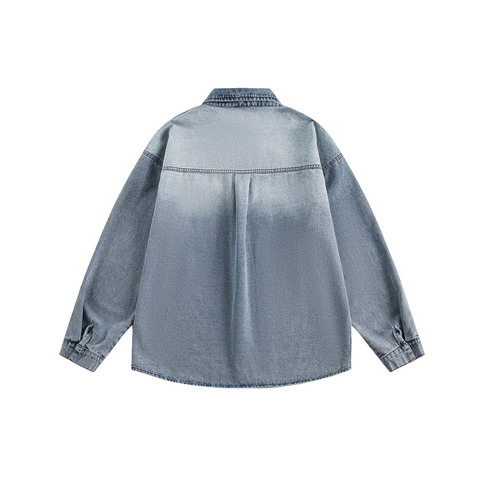 Back view of a light blue denim shirt with long sleeves, a wide yoke, center pleat, and curved hem.
