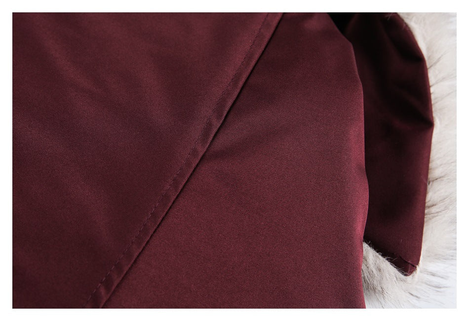 Close-up of a burgundy garment seam and edge beside pale fur trim.