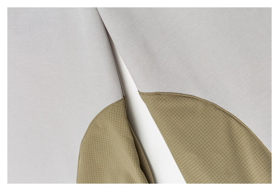 Curved tan mesh inserts meet pale gray panels on the garment.