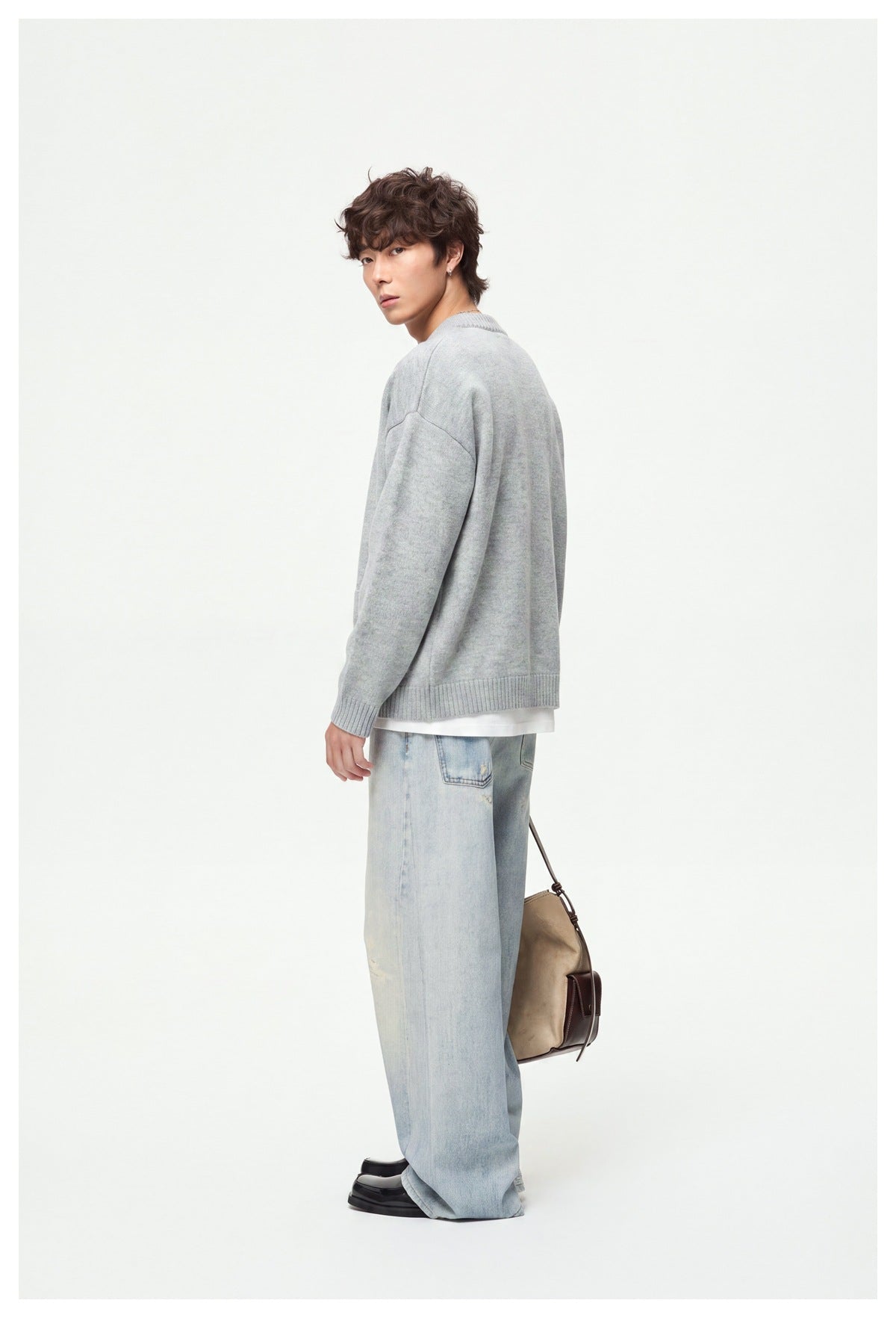 Model in a light gray cardigan, turned to show its plain back and relaxed fit.